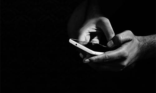 Grayscale image of a person holding a smartphone.