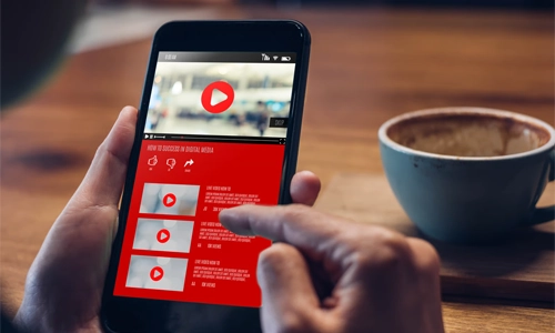 A person uses their index finger to scroll through a list of videos on a black smartphone.