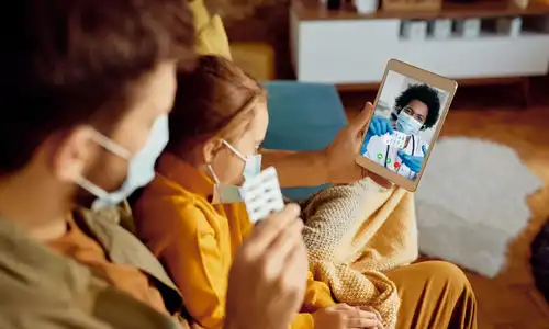 Parent and child attending an online telehealth consultation with a doctor through a tablet at home