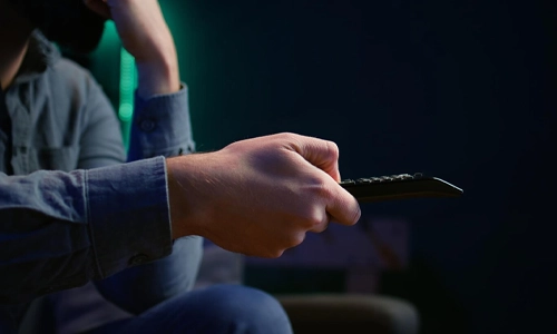 Close-up of a Man’s hand sitting on a sofa and using a remote control
