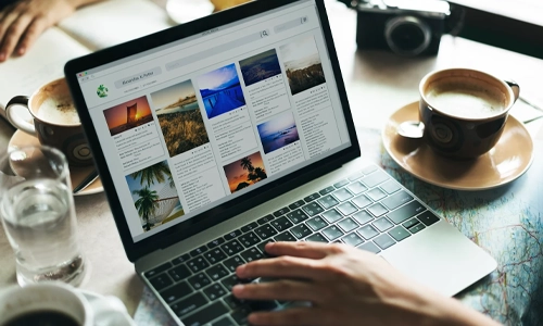 Person browsing web on a laptop with coffee cup aside and above a map