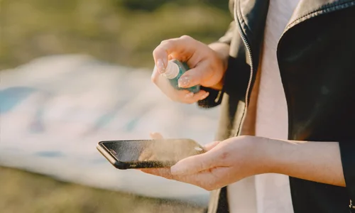 Person cleaning a phone after water exposure, showing real-life risks for water-resistant devices. 